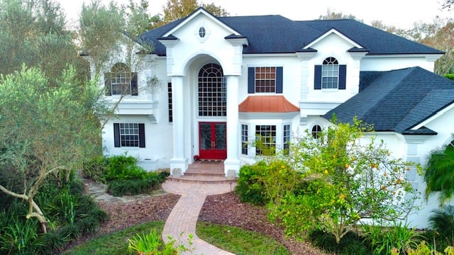 White two-story home with a red front door and dark roof