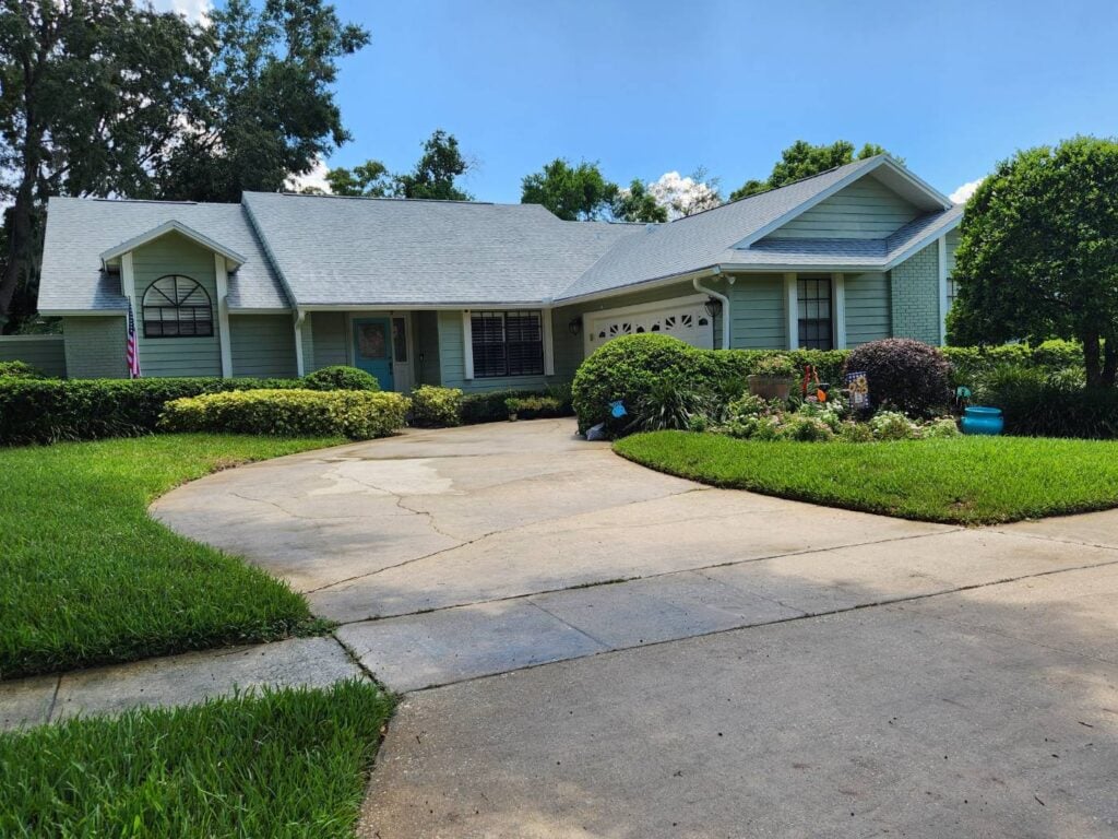 Finished single-story home with sage green lap siding, white trim and a teal front door