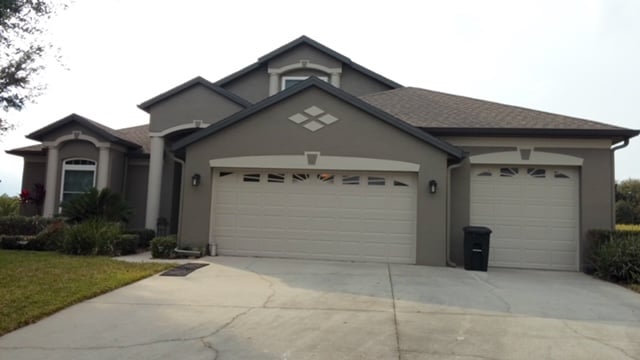 Two-story home with freshly painted gray stucco, cream trim and white garage doors